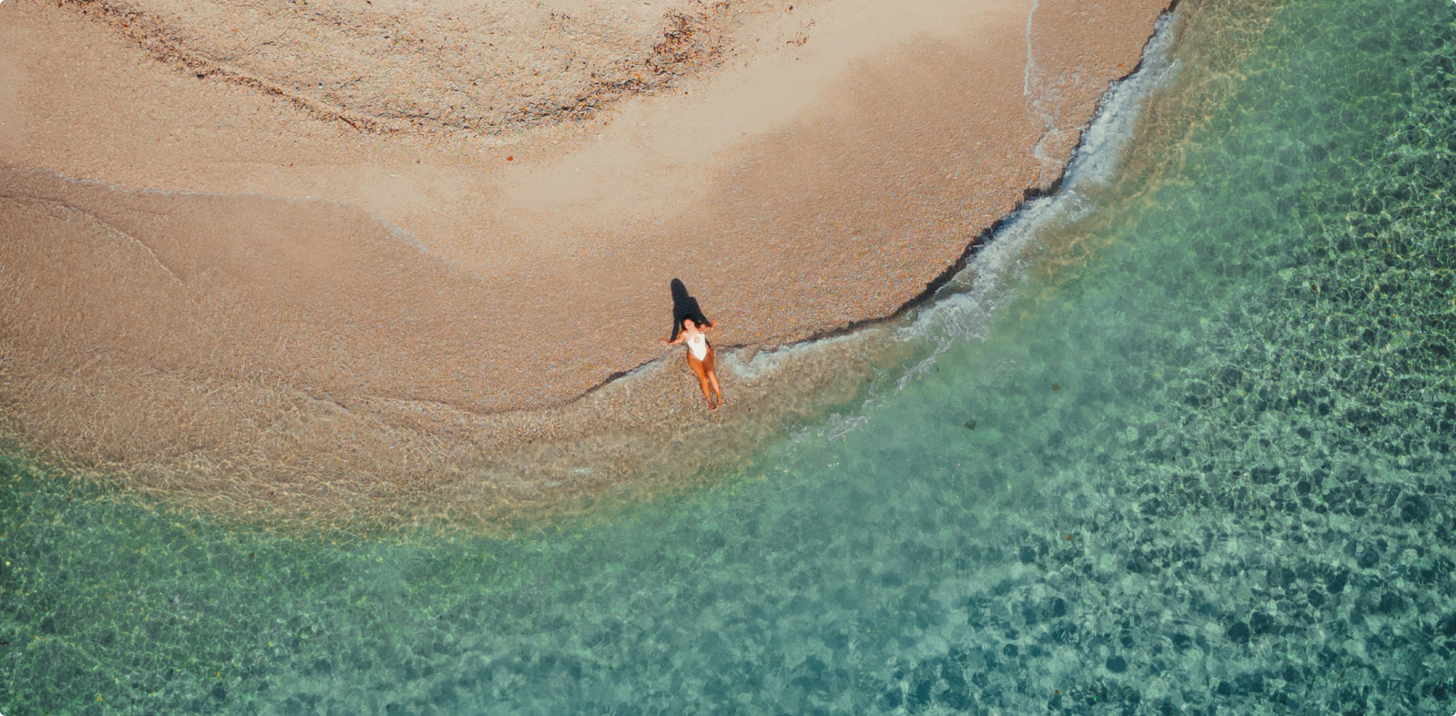 Top down view of a beach with a woman laying down in the water